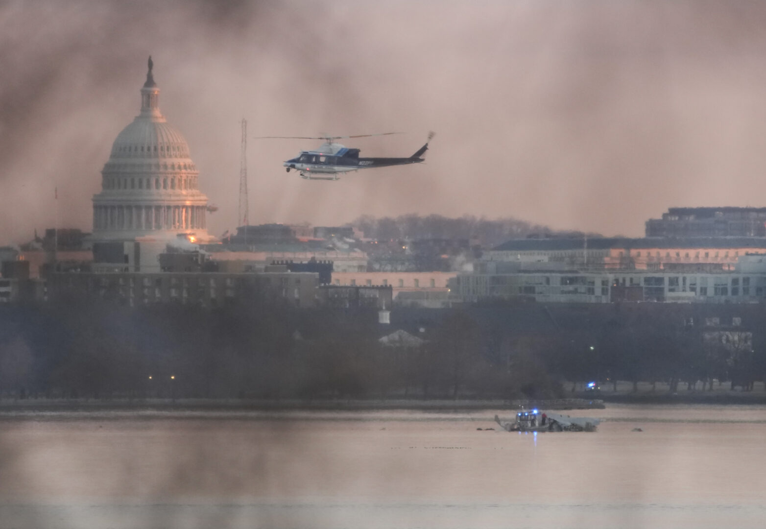 A helicopter flies near the crash site of the American Airlines plane on the Potomac River after the plane crashed on approach to Reagan National Airport on Wednesday evening.