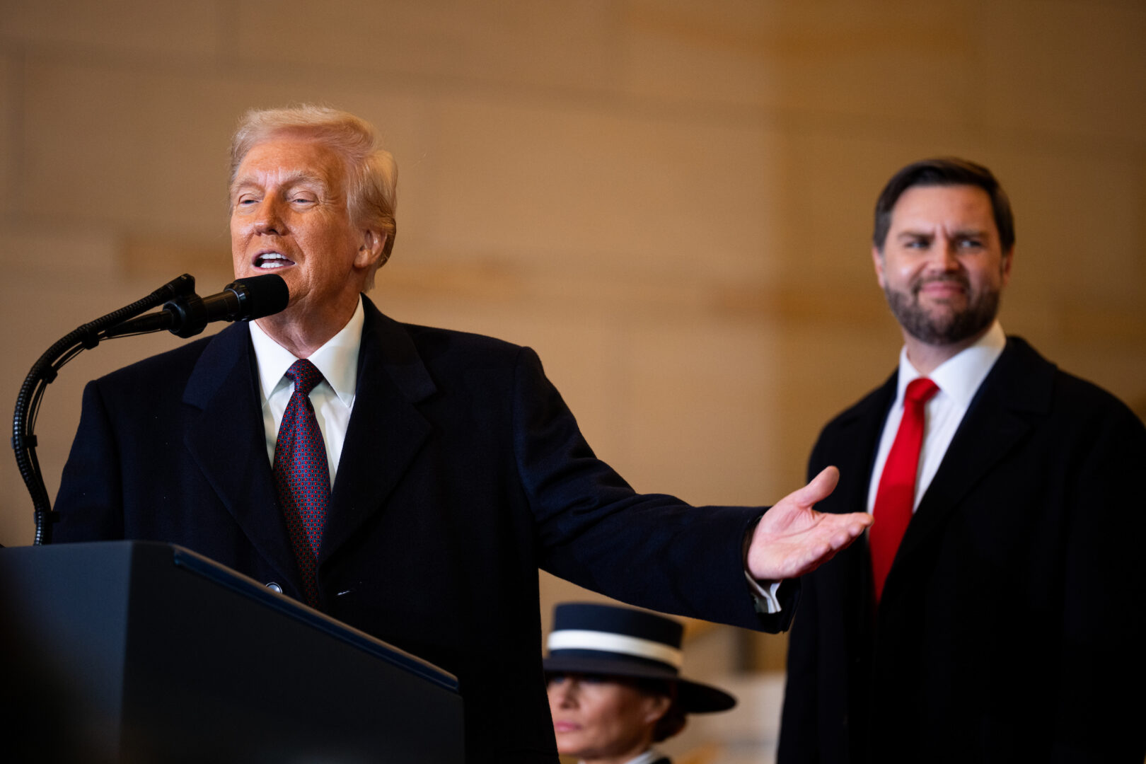 President Donald Trump addresses the crowd in the Emancipation Hall overflow area after being sworn in as the 47th president on Monday, with first lady Melania Trump and Vice President JD Vance in the background. 