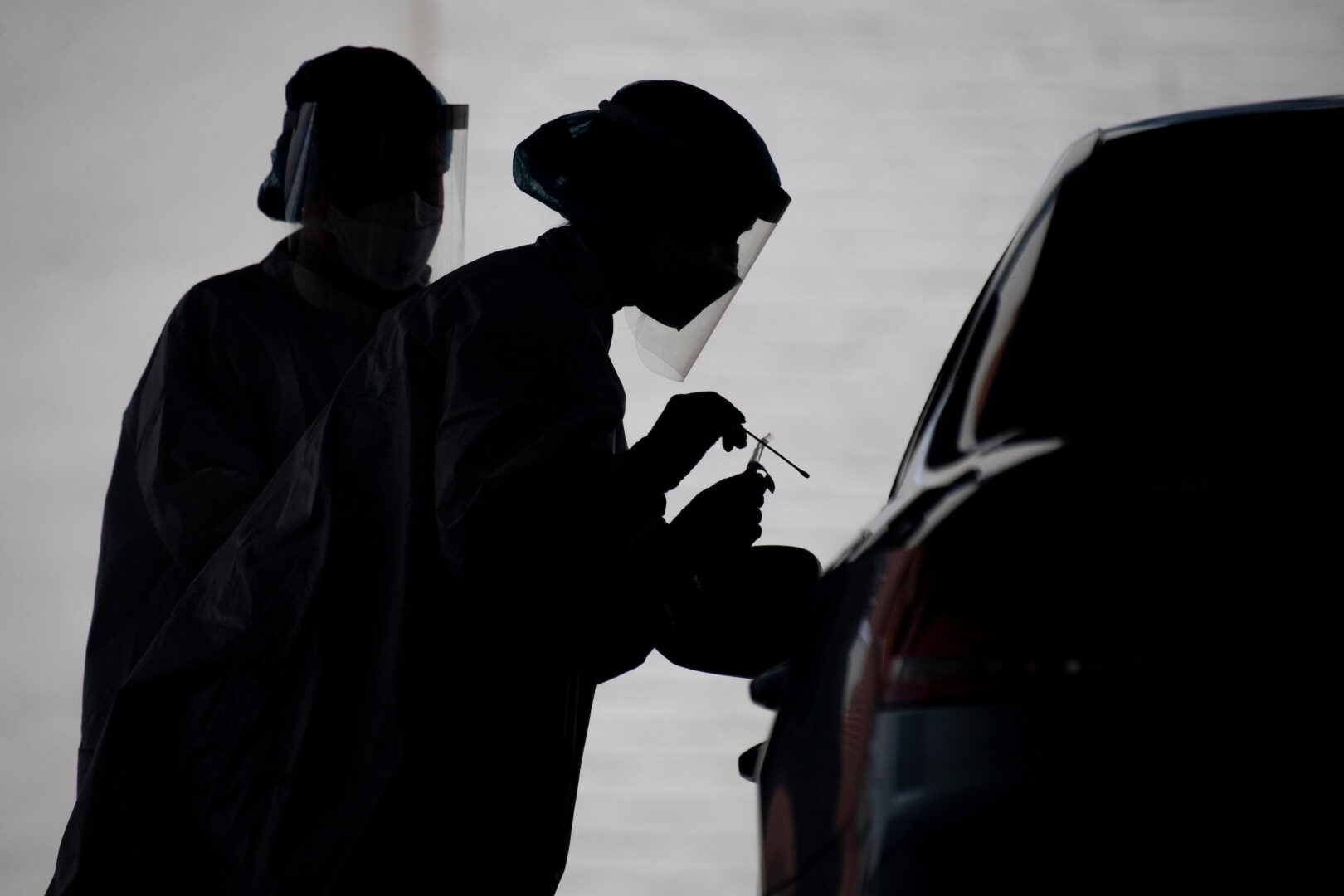 A health care worker conducts a COVID-19 test at a drive-thru testing facility at George Washington University on May 5, 2020. 