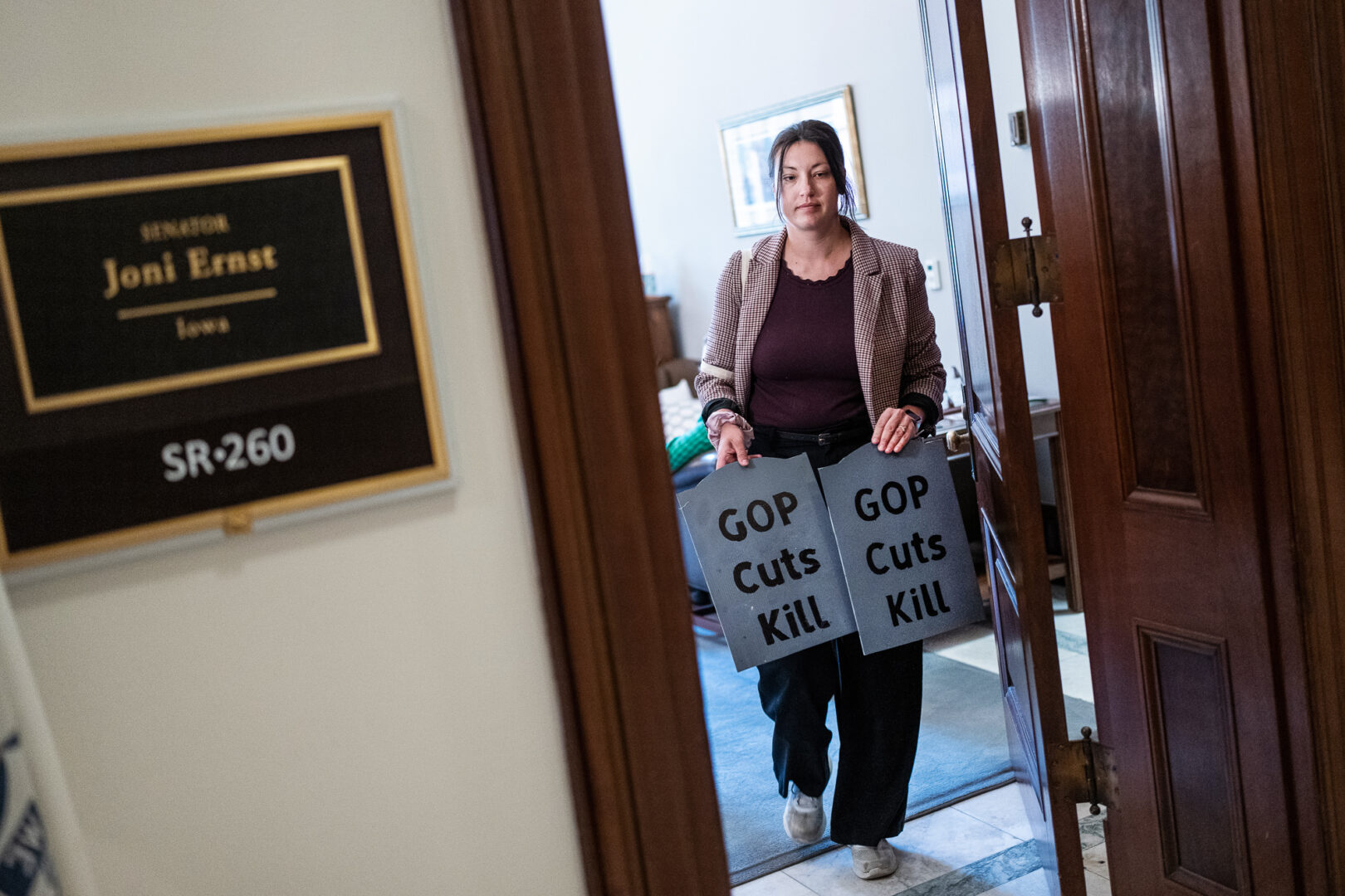 An activist with Save Our Care brings tombstone cutouts to the office of Iowa Republican Sen. Joni Ernst to highlight her comments at a recent town hall on the Republican budget proposal.