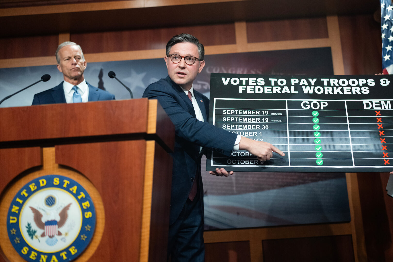 Speaker Mike Johnson, R-La., holds up a chart about paying the military and federal workers during a news conference with Senate Majority Leader John Thune, R-S.D., in the Capitol on Oct. 10.