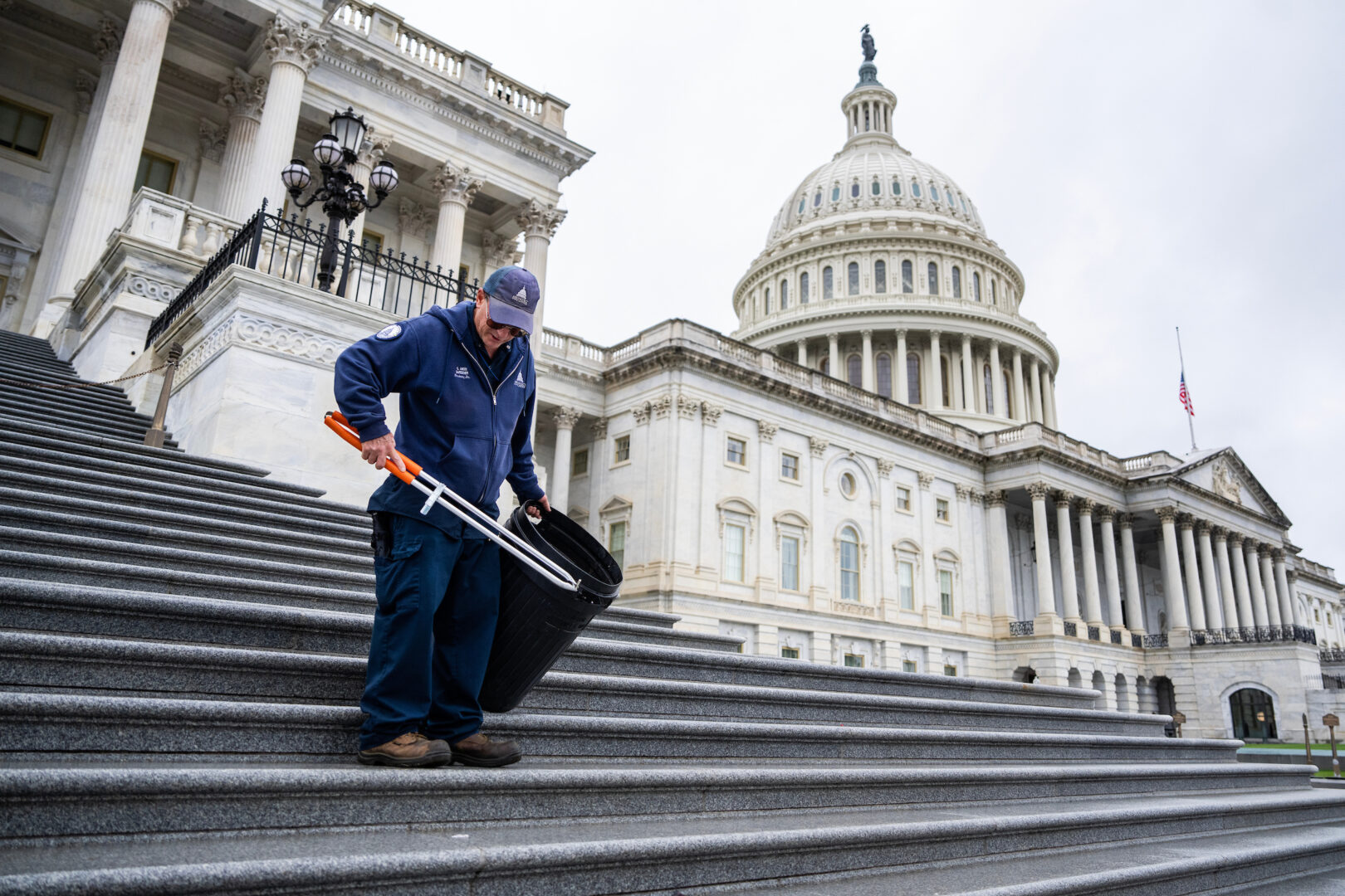 An Architect of the Capitol worker picks up trash on the Capitol steps on May 22. (Tom Williams/CQ Roll Call)