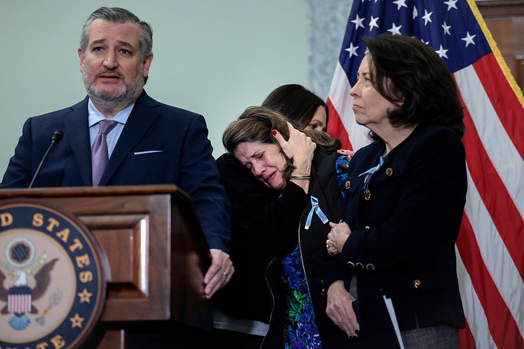 Sen. Ted Cruz, left, and Sen. Maria Cantwell, right, hold a press conference Monday with families who lost loved ones in the January 2025 DCA plane crash. Christina Stovall, third from left, who lost her son Michael "Mikey" Bret Stovall, is comforted by Laura Augendre, who lost her cousin, Peter Livingston and his family. (Heather Diehl/Getty Images)