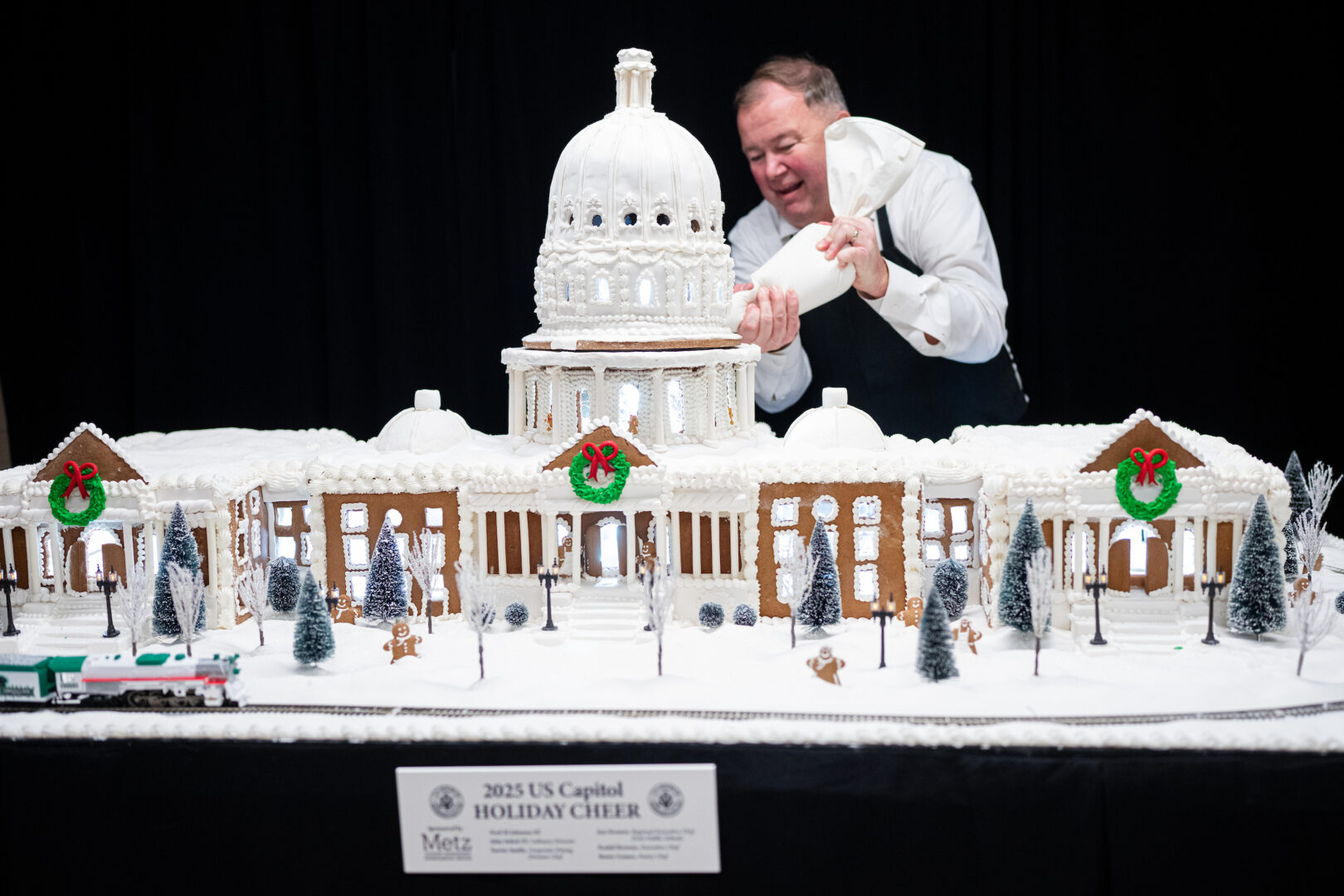Chef Fred Johnson adds icing around the base of the sugary dome on top of this year’s Capitol gingerbread model.