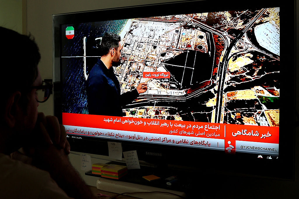 An Iranian man in Tehran watches the news on Iranian state TV on Monday. (AFP via Getty Images)