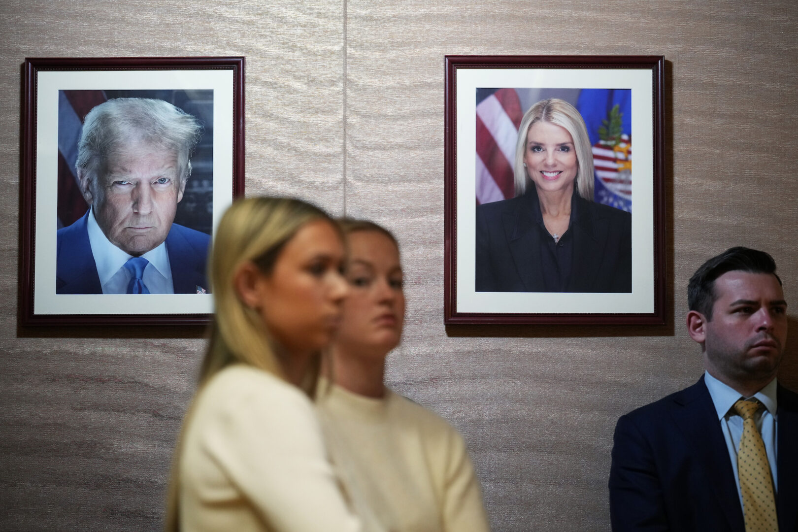 Pictures of President Donald Trump and former Attorney General Pamela Bondi are seen as Acting Attorney General Todd Blanche conducts a news conference at the Justice Department on Tuesday. 